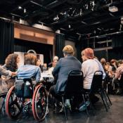 People gathered together sitting at a chair. One person is in a wheelchair.