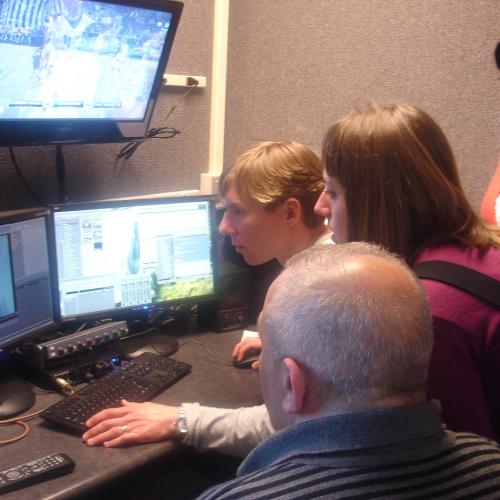 Four participants looking at monitors in a newsroom.