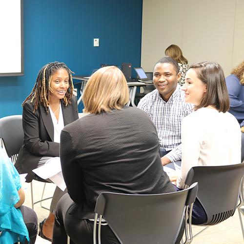 Small groups of employees talk to each other at tables during a staff retreat.