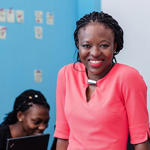 A participants who is smiling in front of a group of girls who are using laptops.