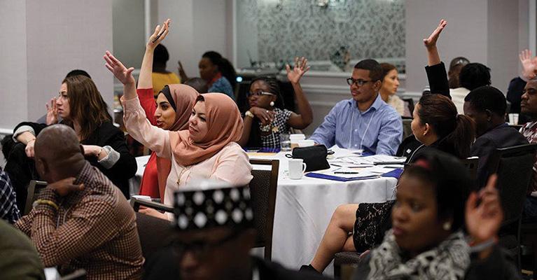 People raising their hands at a conference.